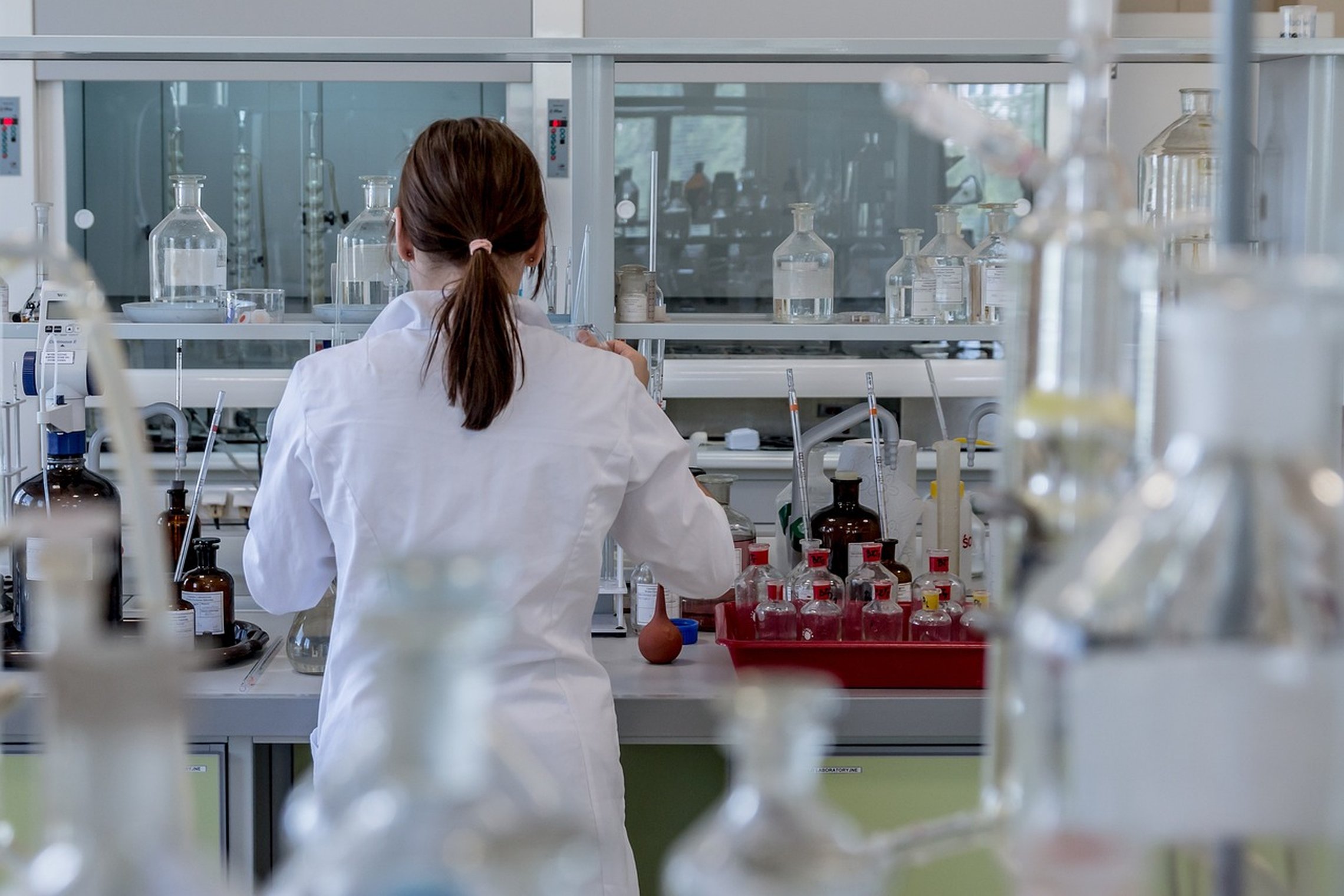 Moteris stovi nugara laboratorijoje tarp mėgintuvėlių