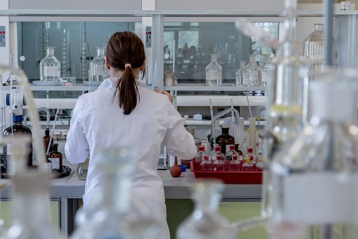 Moteris stovi nugara laboratorijoje tarp mėgintuvėlių